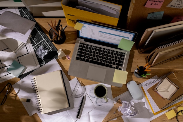Vista da mesa de escritório com espaço de trabalho bagunçado e laptop