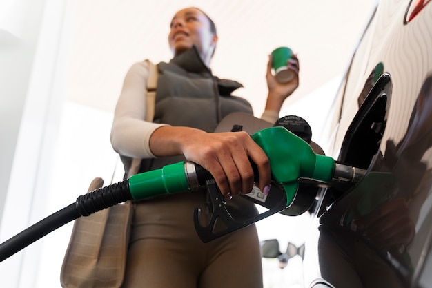 Foto grátis vista da mulher com carro no posto de gasolina