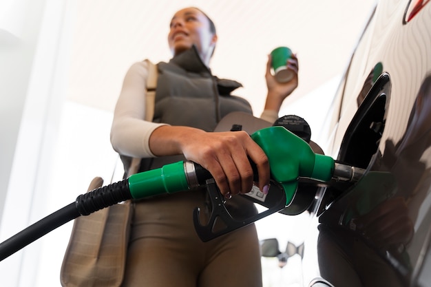 Vista da mulher com carro no posto de gasolina