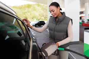 Foto grátis vista da mulher com carro no posto de gasolina