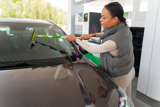 Foto grátis vista da mulher com carro no posto de gasolina