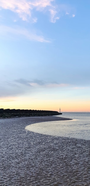 Vista da praia em Liverpool ao pôr do sol, fileiras de quebra-mares, Reino Unido