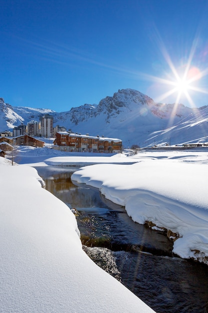 Vista da vila de Tignes com sol e riacho, França.