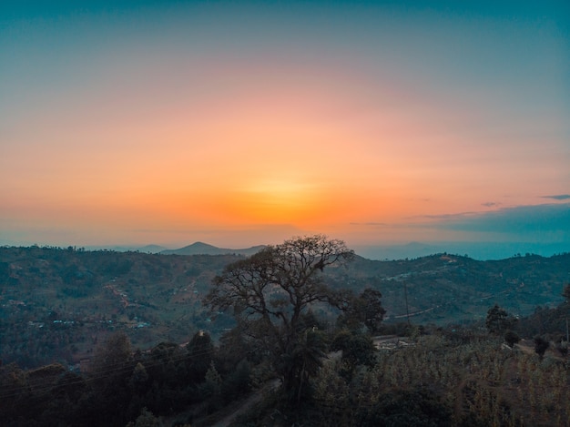 Vista das colinas cobertas de árvores com o pôr do sol