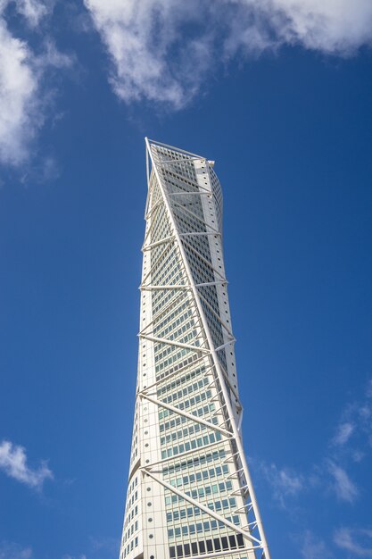 Vista de baixo ângulo do Turning Torso sob um céu azul e luz do sol em Malmo, na Suécia