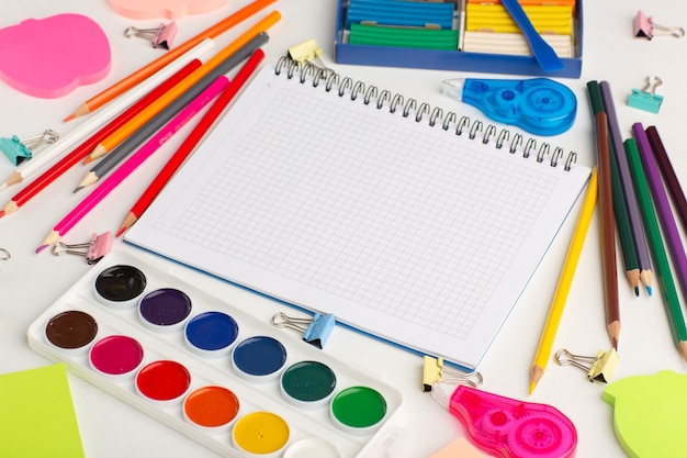 Foto grátis vista de cima a baixo lápis coloridos com tintas e adesivos na arte de mesa branca desenhando tinta colorida