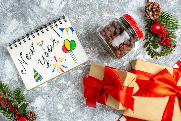 Vista de cima, ano novo escrito no caderno, cereal de presentes de Natal na jarra na mesa cinza