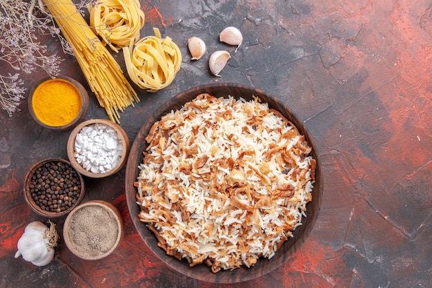 Vista de cima, arroz cozido junto com temperos em um piso escuro com foto refeição