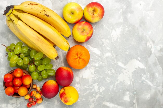 Vista de cima, bananas frescas amarelas frutas suaves e deliciosas com uvas e maçãs em uma mesa branca clara