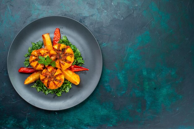 Vista de cima batatas assadas com carne picada e verduras dentro do prato na mesa azul escura.