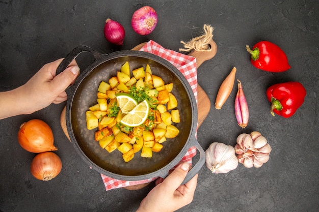 Vista de cima batatas fritas dentro de uma panela com limão no fundo escuro