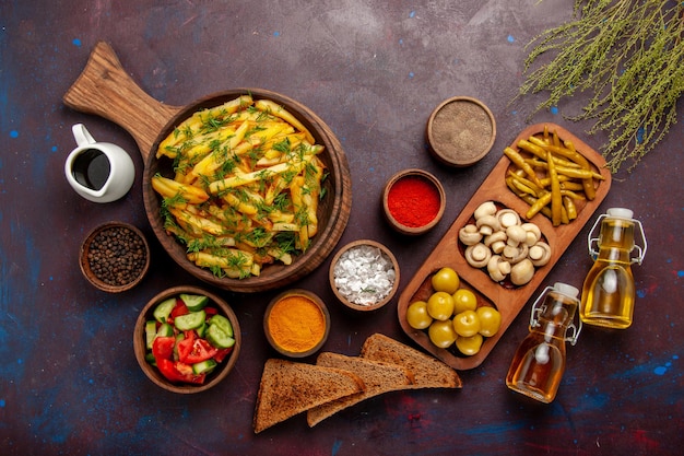 Vista de cima batatas fritas saborosas batatas fritas com verduras e temperos diferentes na superfície escura