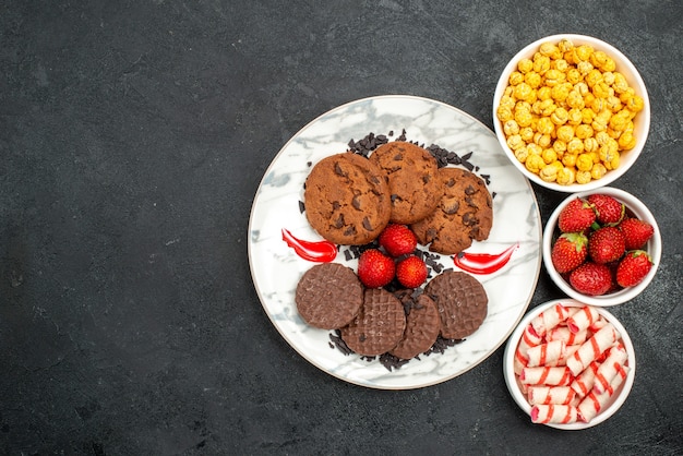 Vista de cima, biscoitos de chocolate saborosos com doces em fundo escuro, bolo de açúcar, biscoito doce