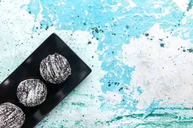 Vista de cima, bolas de chocolate deliciosas, bolos de chocolate com cobertura na superfície azul claro