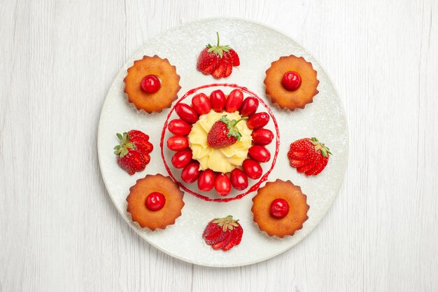 Vista de cima bolinhos com frutas dentro de um prato na mesa branca