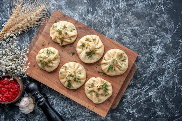 Vista de cima bolinhos crus com carne e molho de tomate na superfície cinza massa refeição bolo torta prato jantar cozinha cozinhar carne