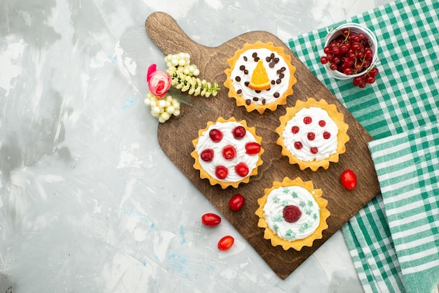 Vista de cima bolinhos de creme com frutas frescas na mesa cinza claro açúcar doce