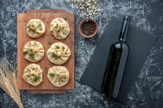 Vista de cima bolinhos de massa crus com carne e garrafa de vinho na superfície cinza massa refeição bolo jantar cozinha carne cozinhar prato