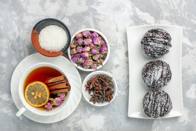 Vista de cima bolinhos deliciosos bolinhos de chocolate com xícara de chá no fundo branco