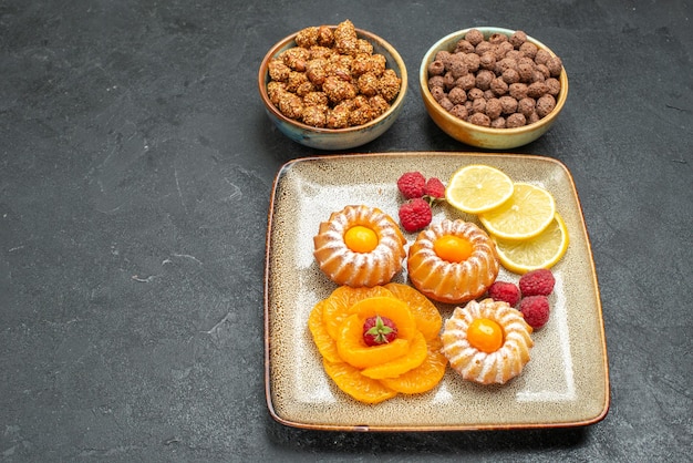 Vista de cima, bolinhos deliciosos com rodelas de limão, tangerinas e doces no espaço cinza