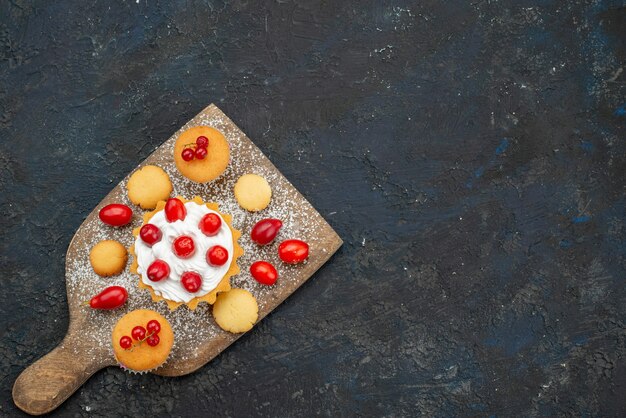 Vista de cima bolinhos gostosos com creme e frutas frescas na superfície escura biscoitos doces bolo açúcar