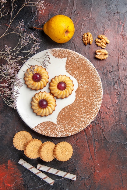 Vista de cima bolinhos saborosos dentro do prato na mesa escura bolo biscoitos doces açúcar