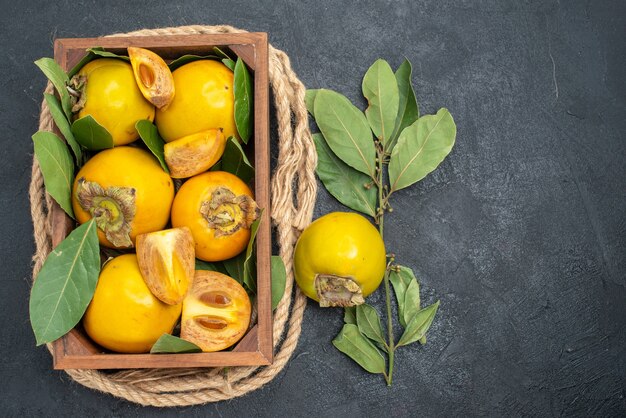 Vista de cima caqui doce fresco dentro da caixa na mesa escura com sabor de fruta madura