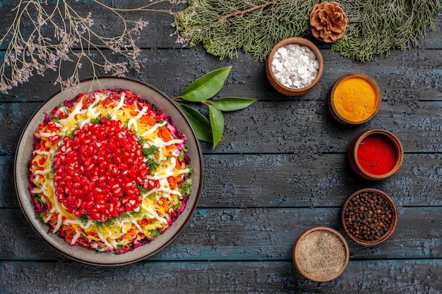 Vista de cima comida saborosa comida saborosa de Natal no lado esquerdo e cinco tigelas de especiarias coloridas no lado direito ao lado dos ramos de abeto com cones