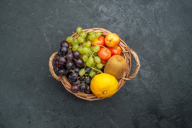 Vista de cima composição de frutas diferentes frescas e maduras dentro da cesta no fundo cinza escuro frutas frescas maduras saúde maduras