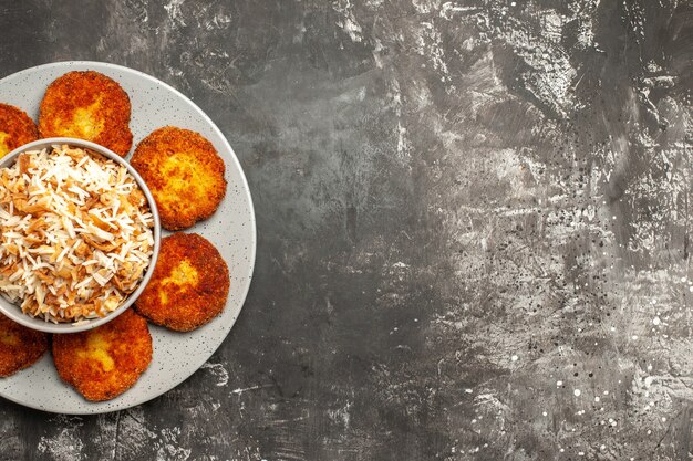 Vista de cima costeletas fritas com arroz cozido em um prato de rissole de superfície clara