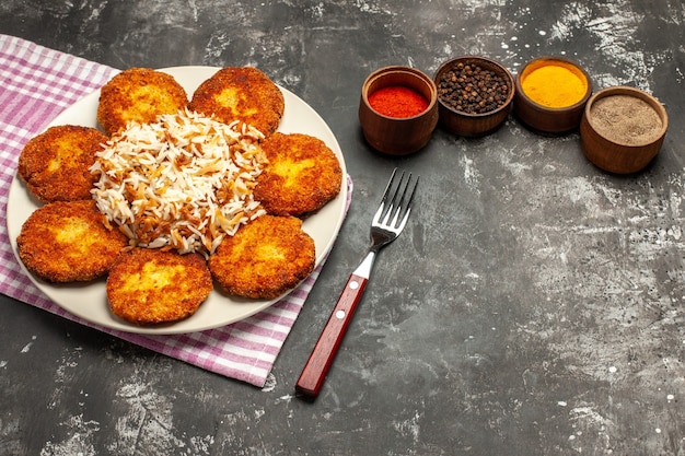 Foto grátis vista de cima, costeletas fritas saborosas com arroz e temperos em uma refeição de rissole de carne de superfície escura