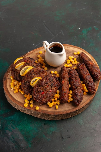 Vista de cima, costeletas saborosas fritas com grãos e rodelas de limão na superfície verde-escura