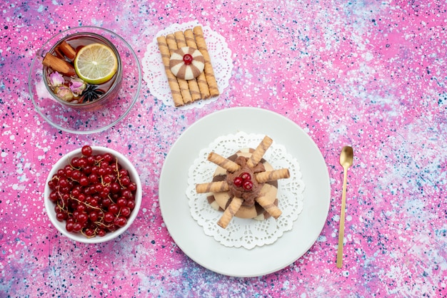 Vista de cima cranberries vermelhas com chá e biscoitos na cor roxa do biscoito backgorund