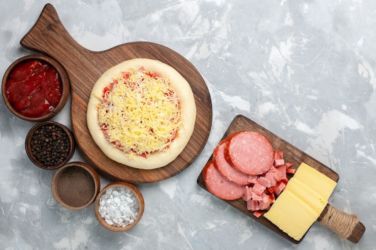 Foto grátis vista de cima da pizza crua com queijo e temperos diferentes na mesa branca clara