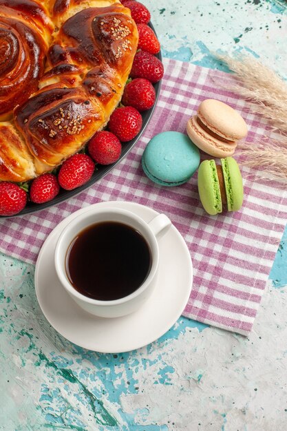 Vista de cima da torta de morango com macarons franceses e chá na superfície azul