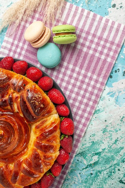 Vista de cima da torta de morango com macarons franceses na mesa azul