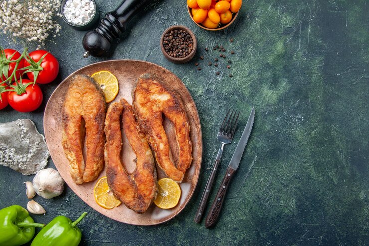 Foto grátis vista de cima de deliciosos peixes fritos e rodelas de limão em um prato marrom pimenta tomate com caule na mesa de cores com espaço livre