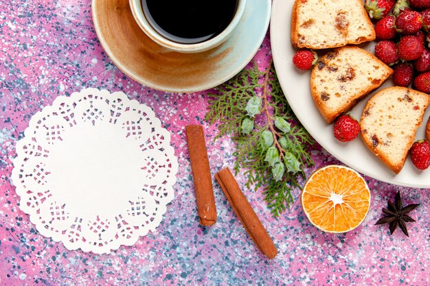 Vista de cima de fatias de bolo com morangos vermelhos frescos e xícara de café na mesa rosa