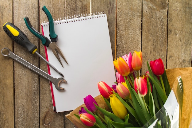 Vista de cima de ferramentas, caderno e flores para o dia do pai