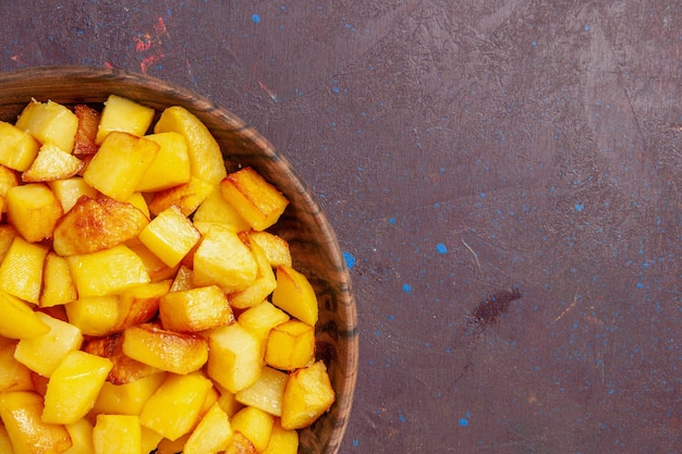 Vista de cima de perto em fatias de batatas dentro de um prato marrom no espaço escuro