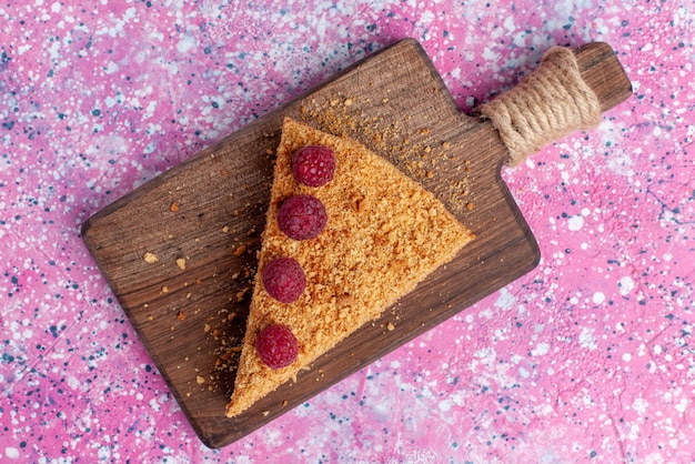 Vista de cima de perto uma fatia de bolo assada e doce com framboesas na mesa rosa brilhante assar torta de frutas doces