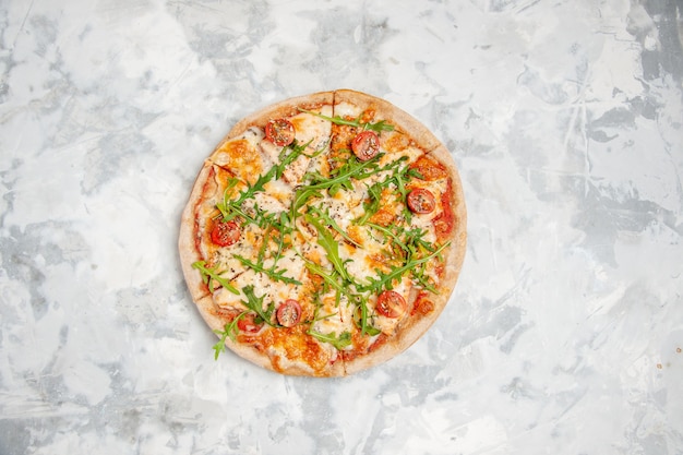 Vista de cima de uma deliciosa pizza com tomates verdes em uma superfície branca manchada com espaço livre