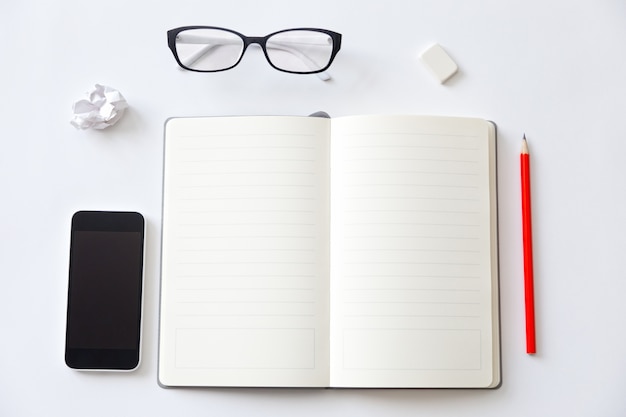 Vista de cima de uma mesa de trabalho com caderno em branco aberto