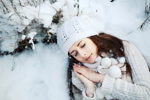 Vista de cima de uma mulher jovem dormindo no chão coberto de neve
