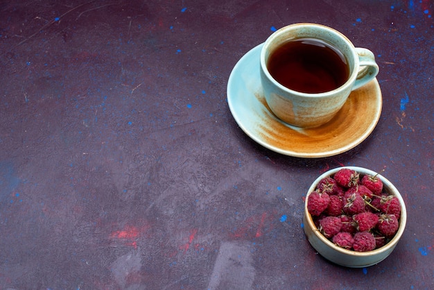 Vista de cima de uma xícara de chá com framboesas frescas na superfície escura