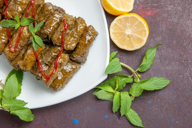 Vista de cima deliciosa folha de dolma carne moída prato dentro de placa em fundo escuro folha prato jantar comida carne