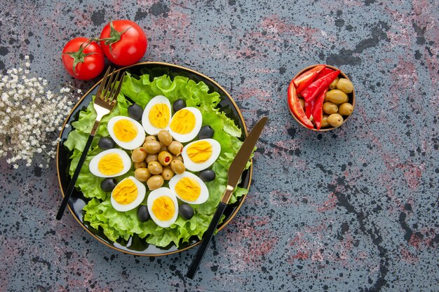 Vista de cima deliciosa salada de ovo com tomate e azeitonas em fundo claro