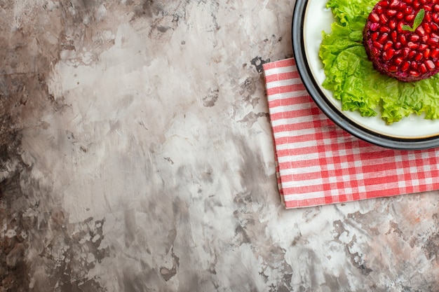 Vista de cima, deliciosa salada de romã redonda em forma de salada verde em fundo claro