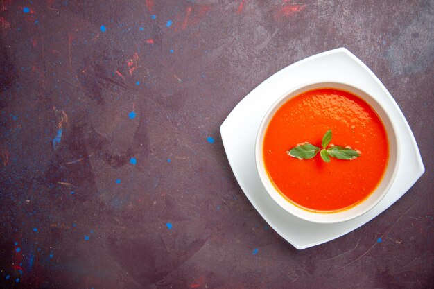 Vista de cima deliciosa sopa de tomate prato saboroso com uma única folha dentro do prato em um fundo escuro prato molho tomate cor sopa