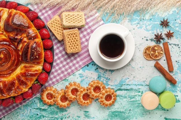 Vista de cima deliciosa torta com biscoitos de morangos vermelhos e waffles na superfície azul